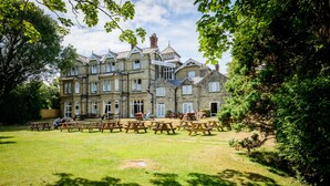 A large, historic building with multiple windows and a well-maintained lawn with picnic tables. - Daish's Hotel (Shanklin)