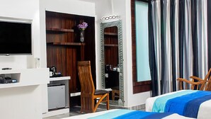 A hotel room with a bed, a desk with a chair, a TV, a mirror, and a window with curtains. - Hotel SGT Plaza (Varanasi)