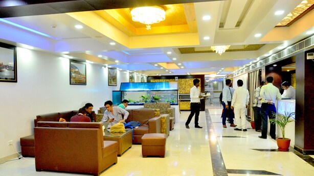 A hotel lobby with sofas, a reception desk, and a large aquarium. - Hotel SGT Plaza (Varanasi)
