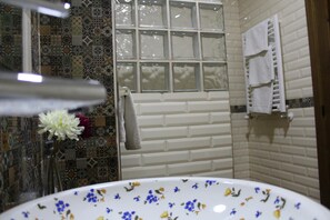 Un baño con ducha, pared de azulejos blancos, ventana y perchero.
