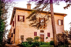 A two-story stone building with a central entrance, a small balcony, and a chimney. - Ca' Lavalle B&B (Urbino)