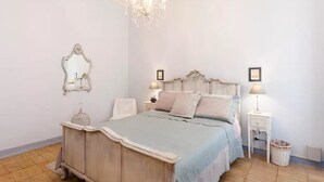 Ein Schlafzimmer mit einem Bett, einer Chandelieber, einem Spiegel und Nachttischen.