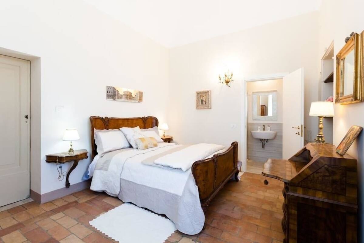 A bedroom with a wooden bed, bedside tables with lamps, a white rug, and a wooden dresser.