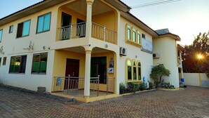 A two-story building with a balcony, a sign indicating it is a guest house, and a paved entrance area. - KCS Guest House (Accra)