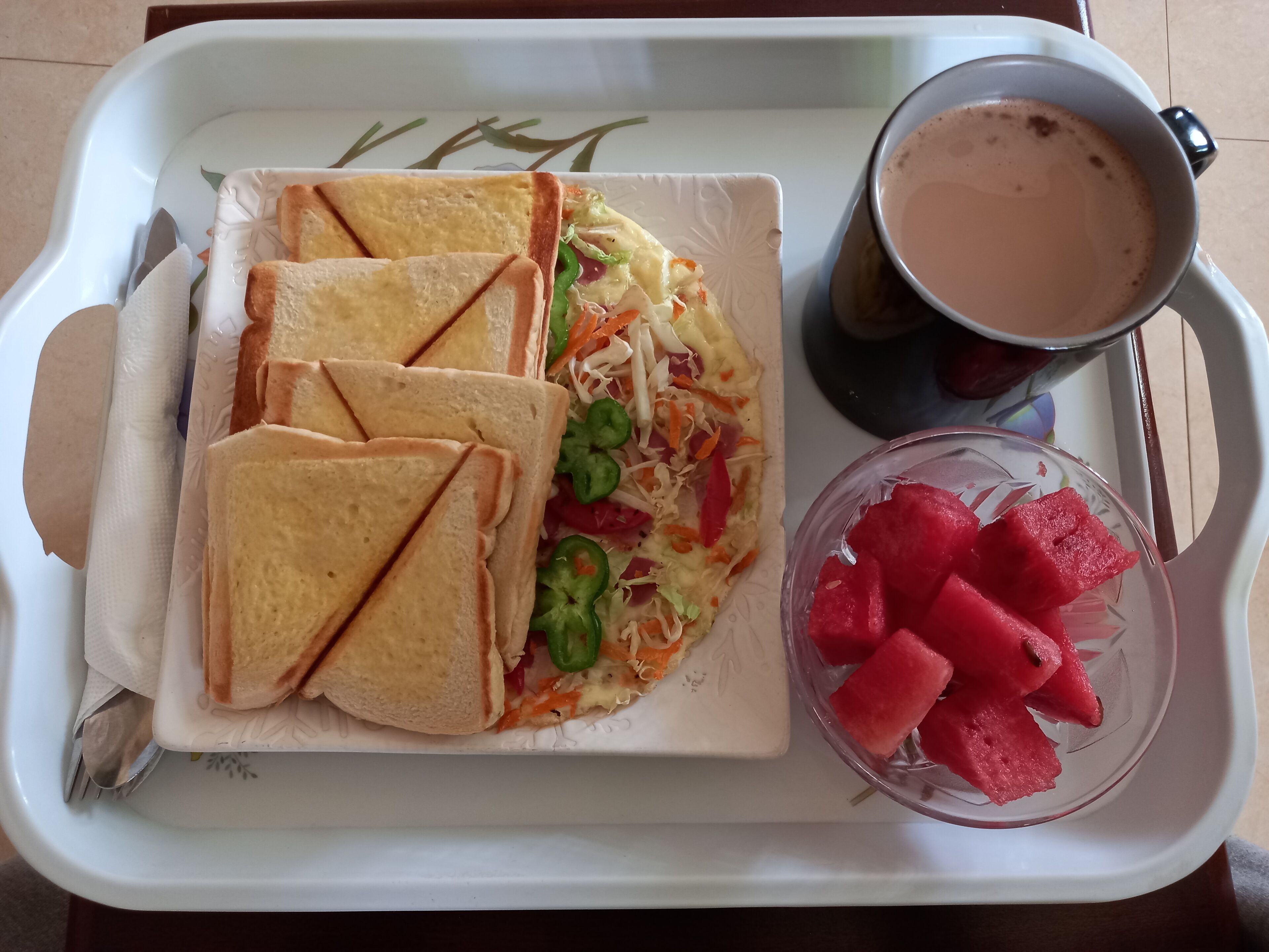 A tray with a sandwich, a bowl of watermelon, and a cup of coffee.