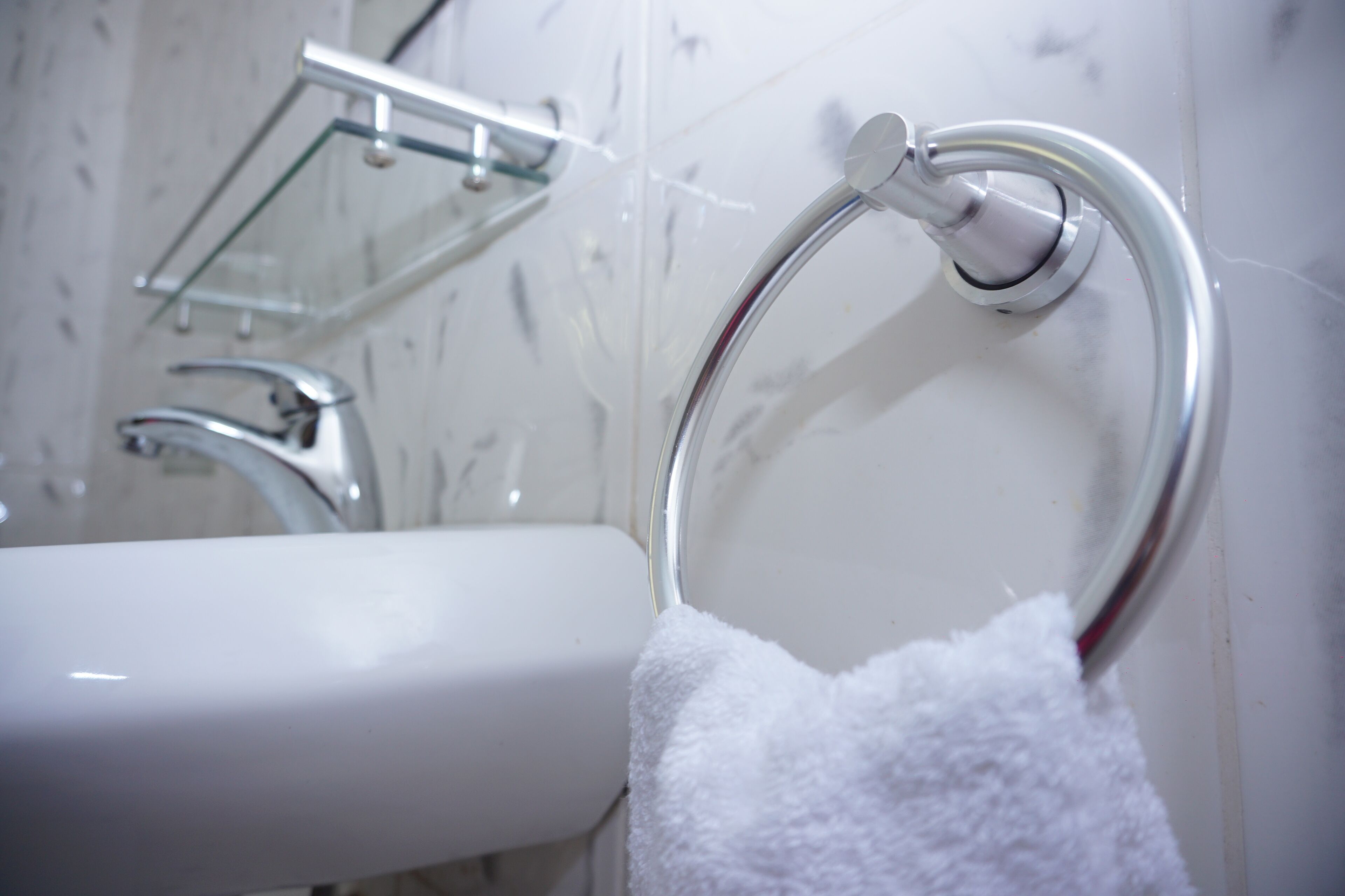 A bathroom with a white sink, chrome towel rack, and a glass shower enclosure.