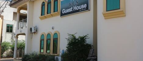 A building with a sign reading "K's Guest House" and a balcony with a railing.