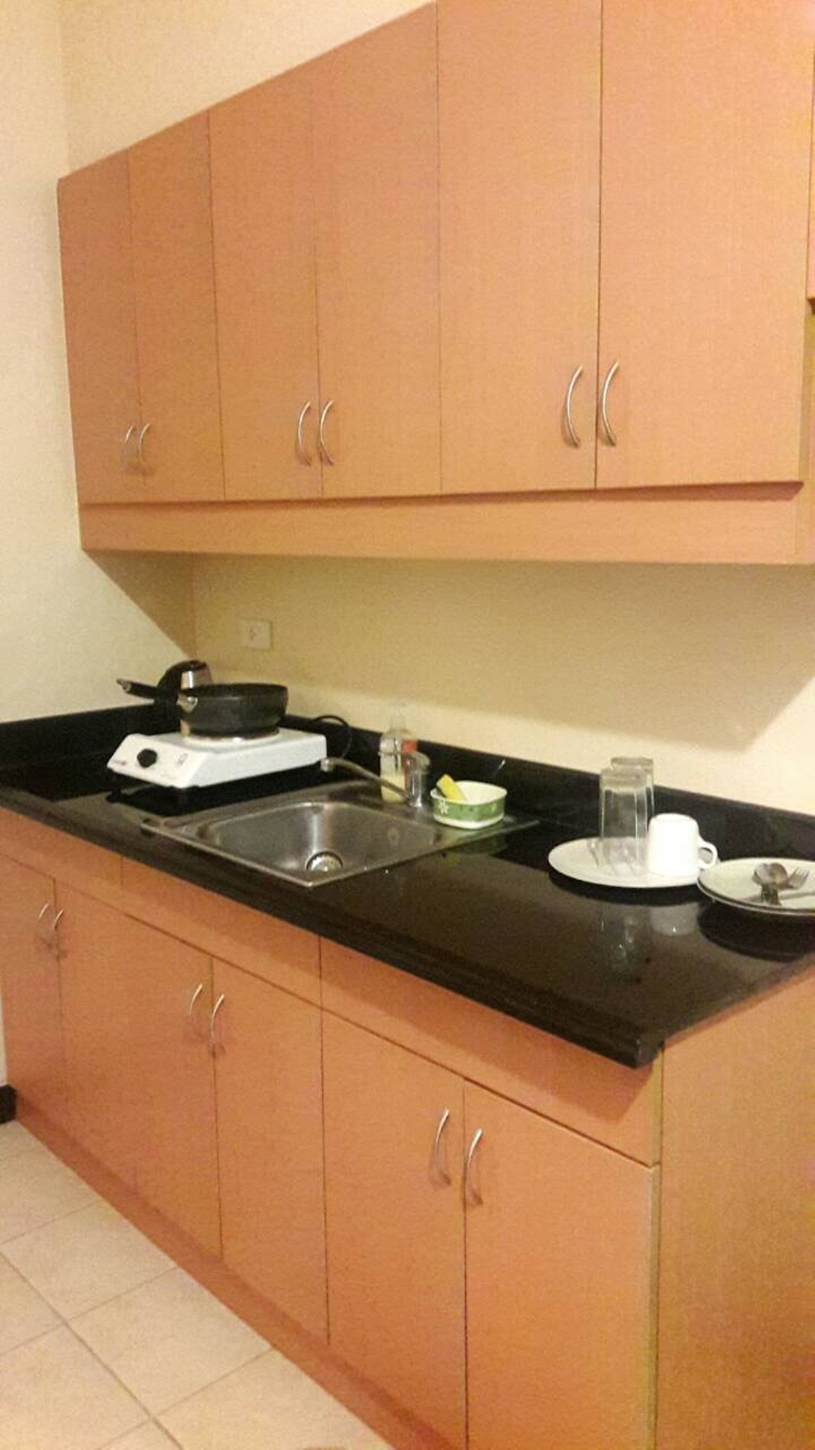 Una cocina con armarios de madera, encimera negra, estufa y fregadero.