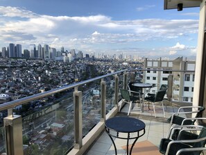 Un balcón con vista a la ciudad, que incluye edificios altos y una zona urbana densamente poblada.