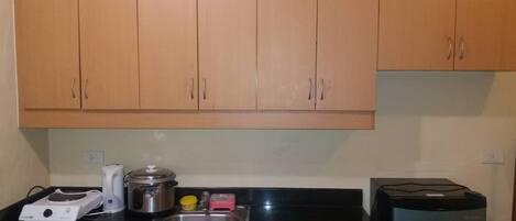 A kitchen with wooden cabinets, a stainless steel sink, a coffee maker, a rice cooker, and a blender.