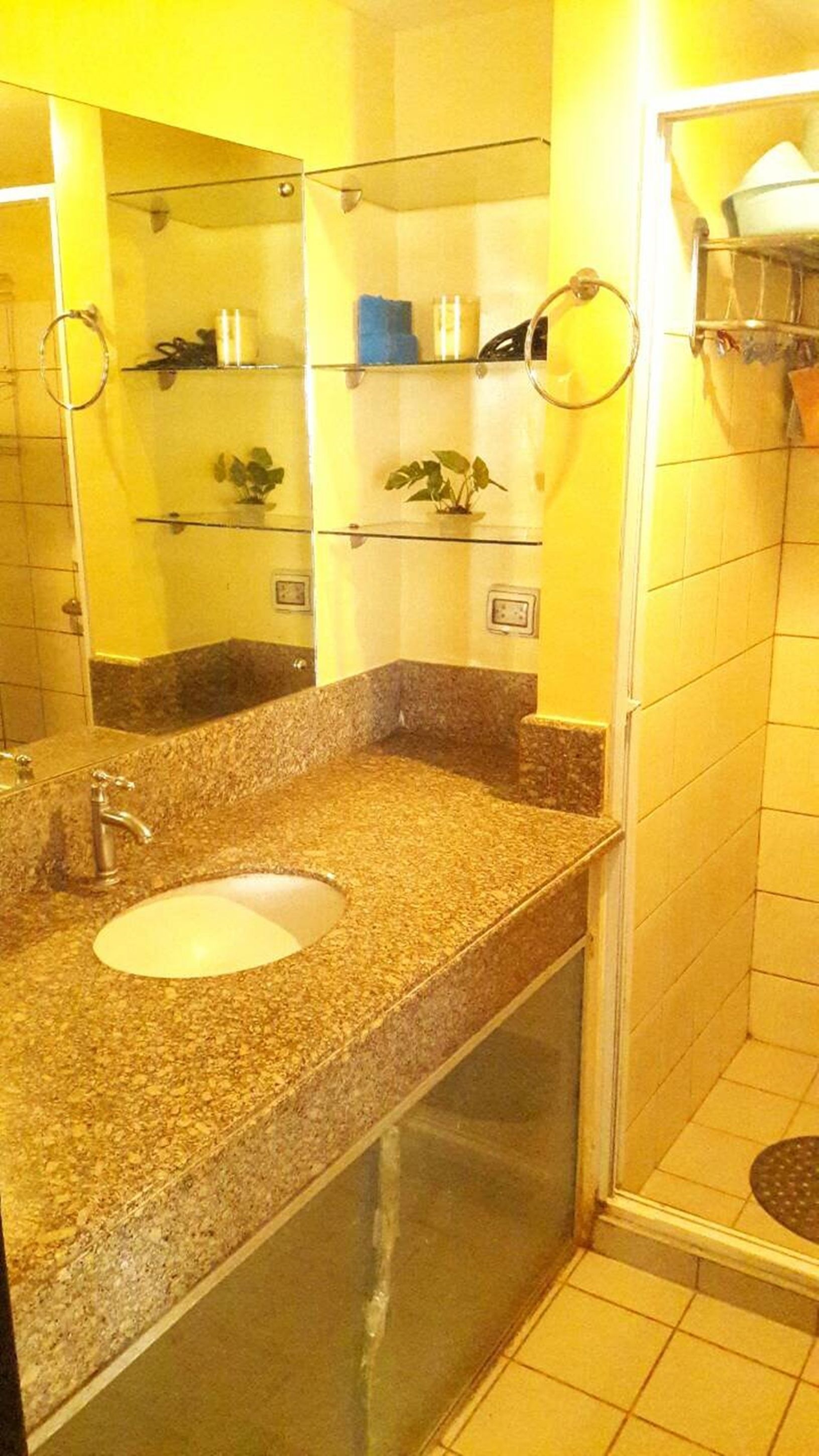 A bathroom with a granite countertop sink, a mirror, and a glass shower enclosure.