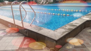Une piscine à l’eau claire, avec des couloirs délimités et des échelles métalliques.
