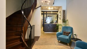 Un escalier menant à un espace d’accueil agrémenté d’une pancarte « Bienvenue », d’un fauteuil bleu et d’une petite table sur laquelle est posé un vase.