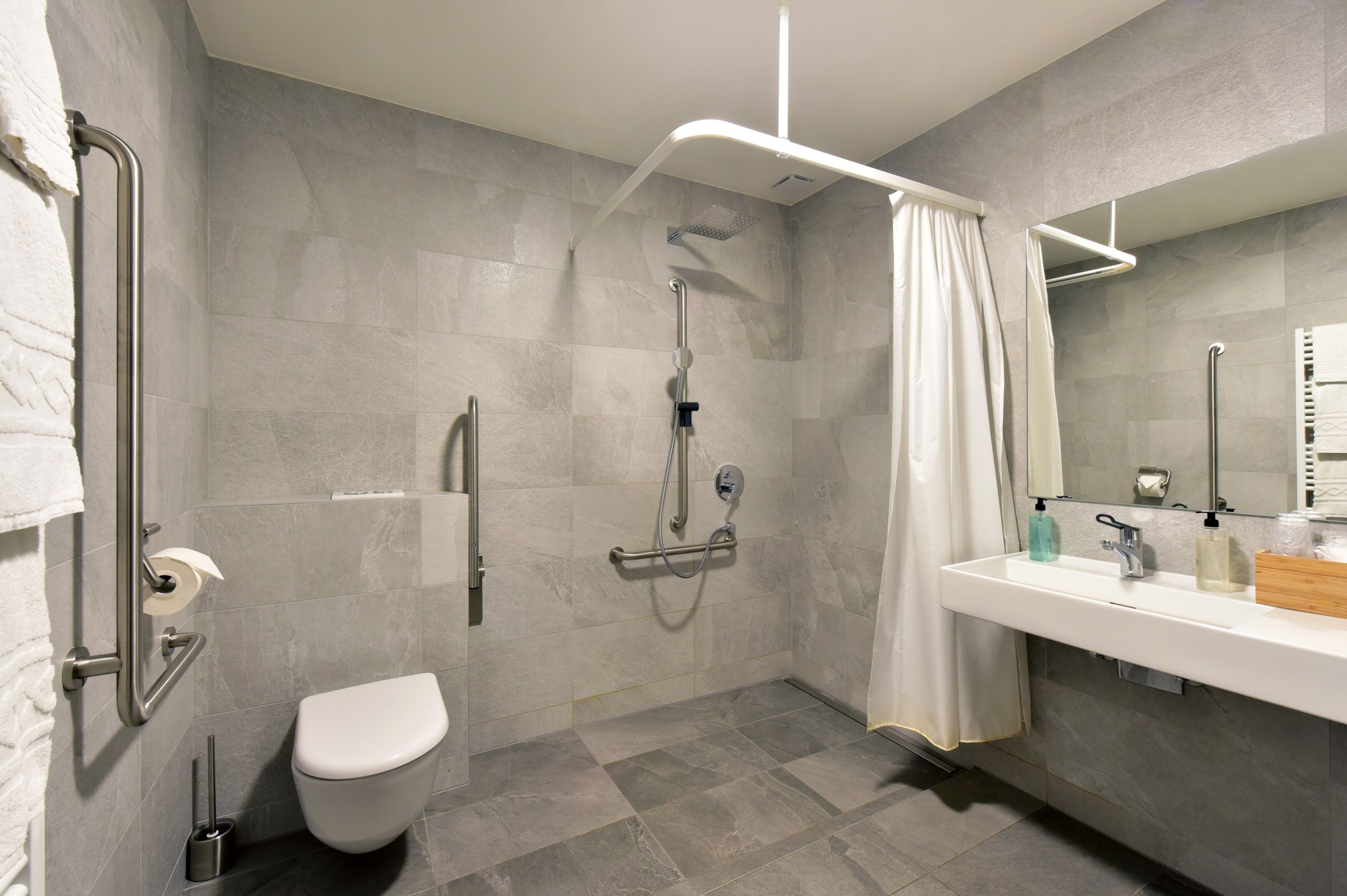 Een moderne badkamer met douche, toilet en wastafel.