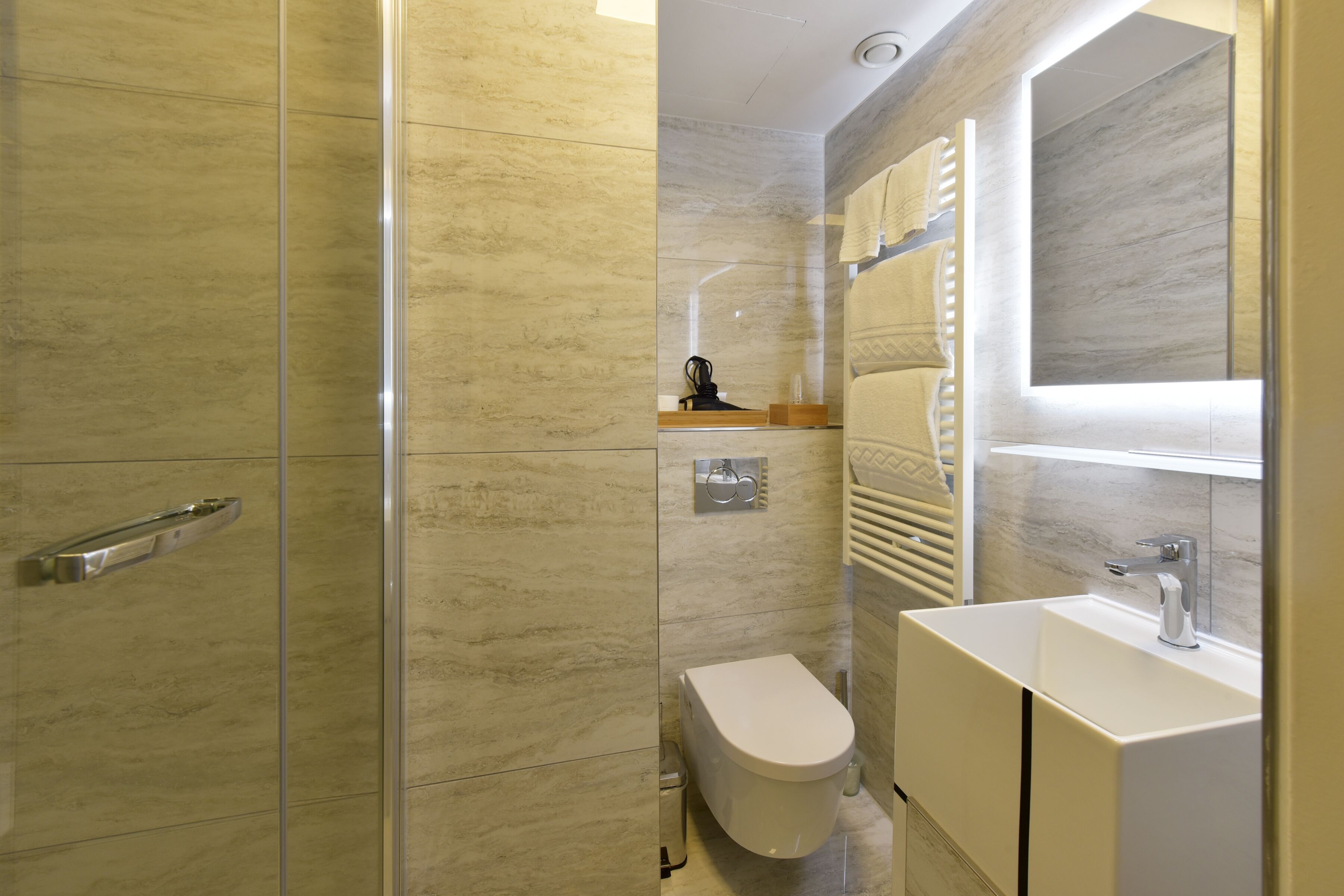 A modern bathroom with a glass shower enclosure, a toilet, and a sink with a mirror above it.