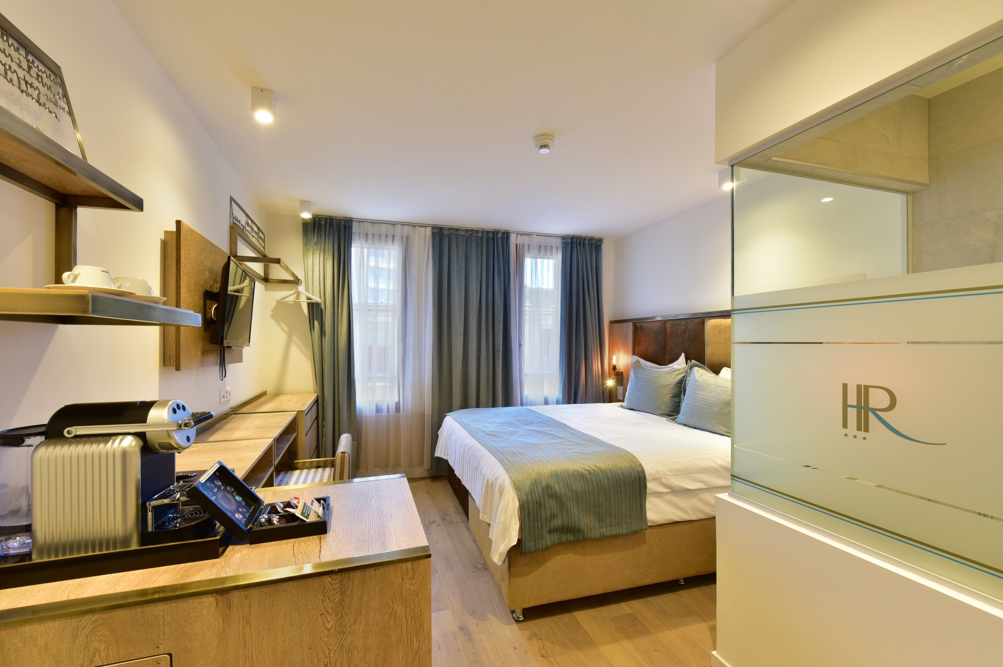 Une chambre d’hôtel avec un lit, un bureau avec un ordinateur, un radiateur et un grand miroir.