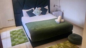 Un dormitorio con cama, mesita de noche, equipo de aire acondicionado y una alfombra verde.