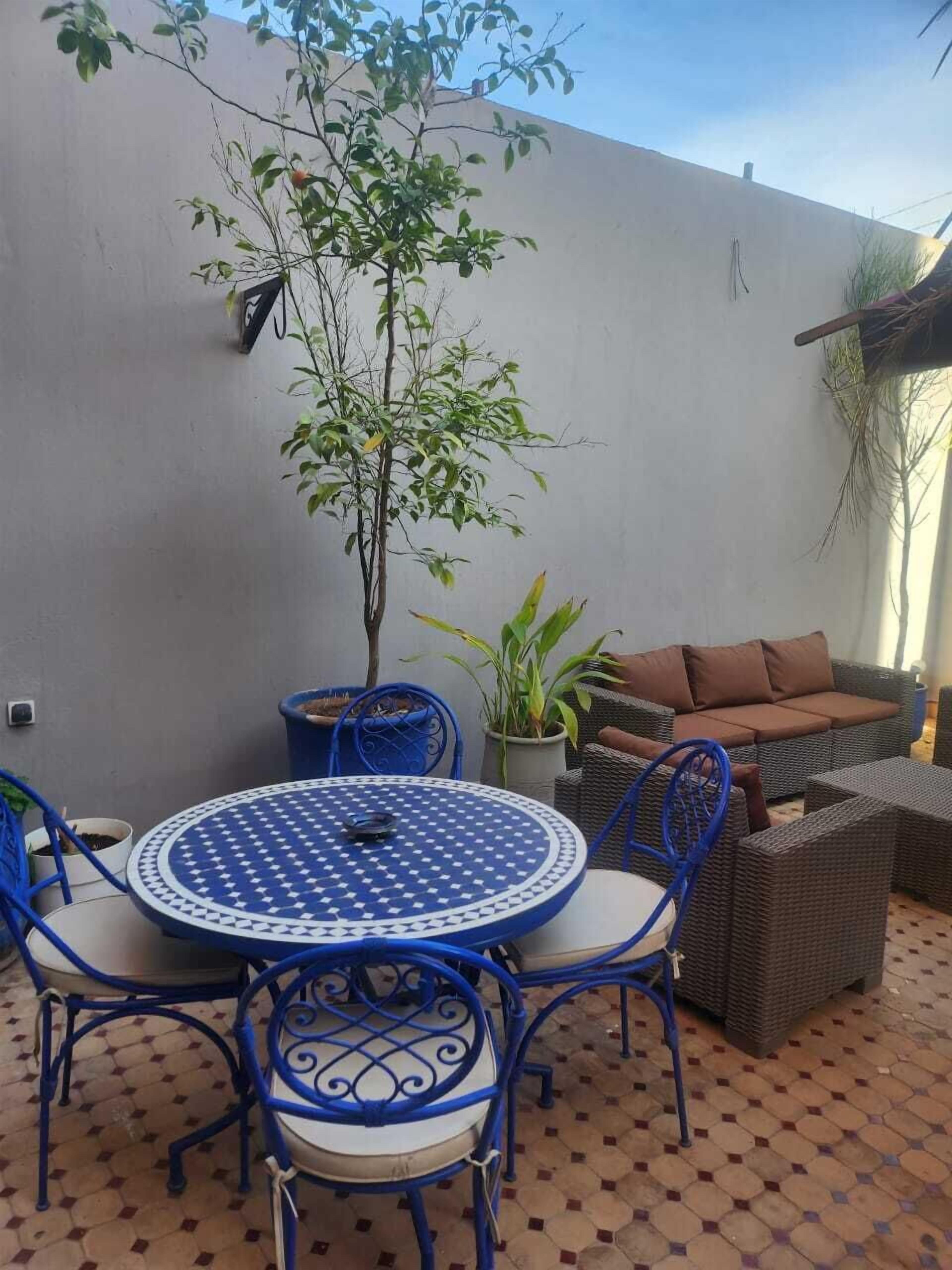 A patio with a round table and chairs, a sofa, and a potted plant.