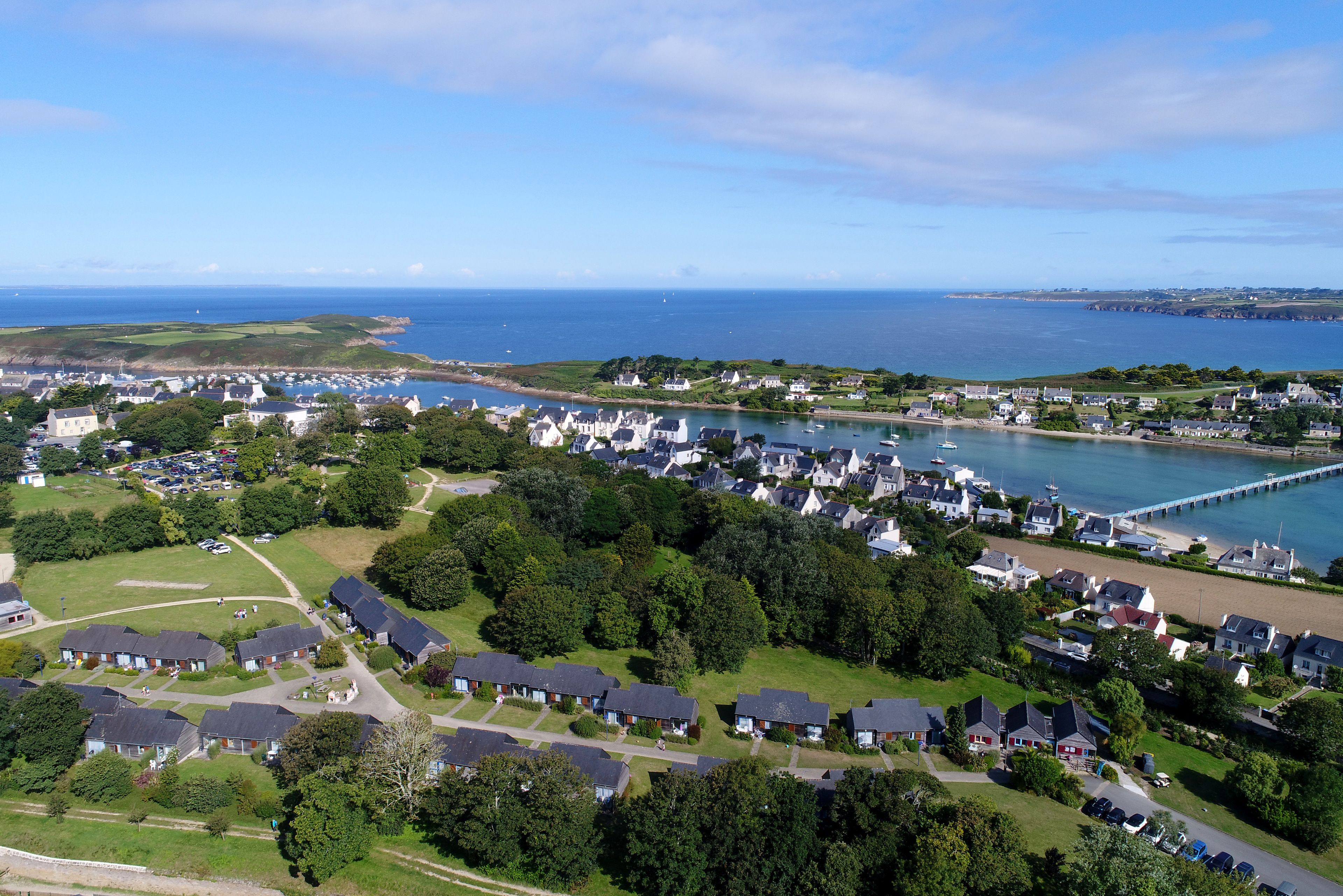 An aerial view of a coastal residential area with houses, a marina, and a pier.