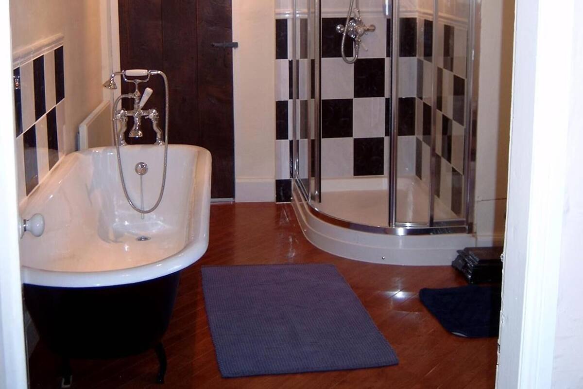 A bathroom with a bathtub, a shower, and a checkered wall.