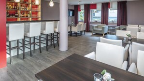 A modern hotel lobby with a bar area, seating arrangements, and a large window with curtains. - Hotel Westerfeld (Hemmingen)