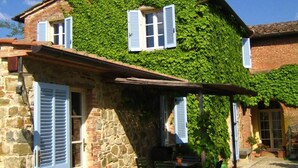 A stone building with a covered patio, a table, and chairs. - Agriturismo Fattoria Santa Vittoria (Foiano della Chiana)