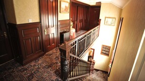 A grand hallway with ornate wooden doors, a patterned carpet, and a classic staircase with a balustrade. - The Cowrie Guest House (Berwick-upon-Tweed)