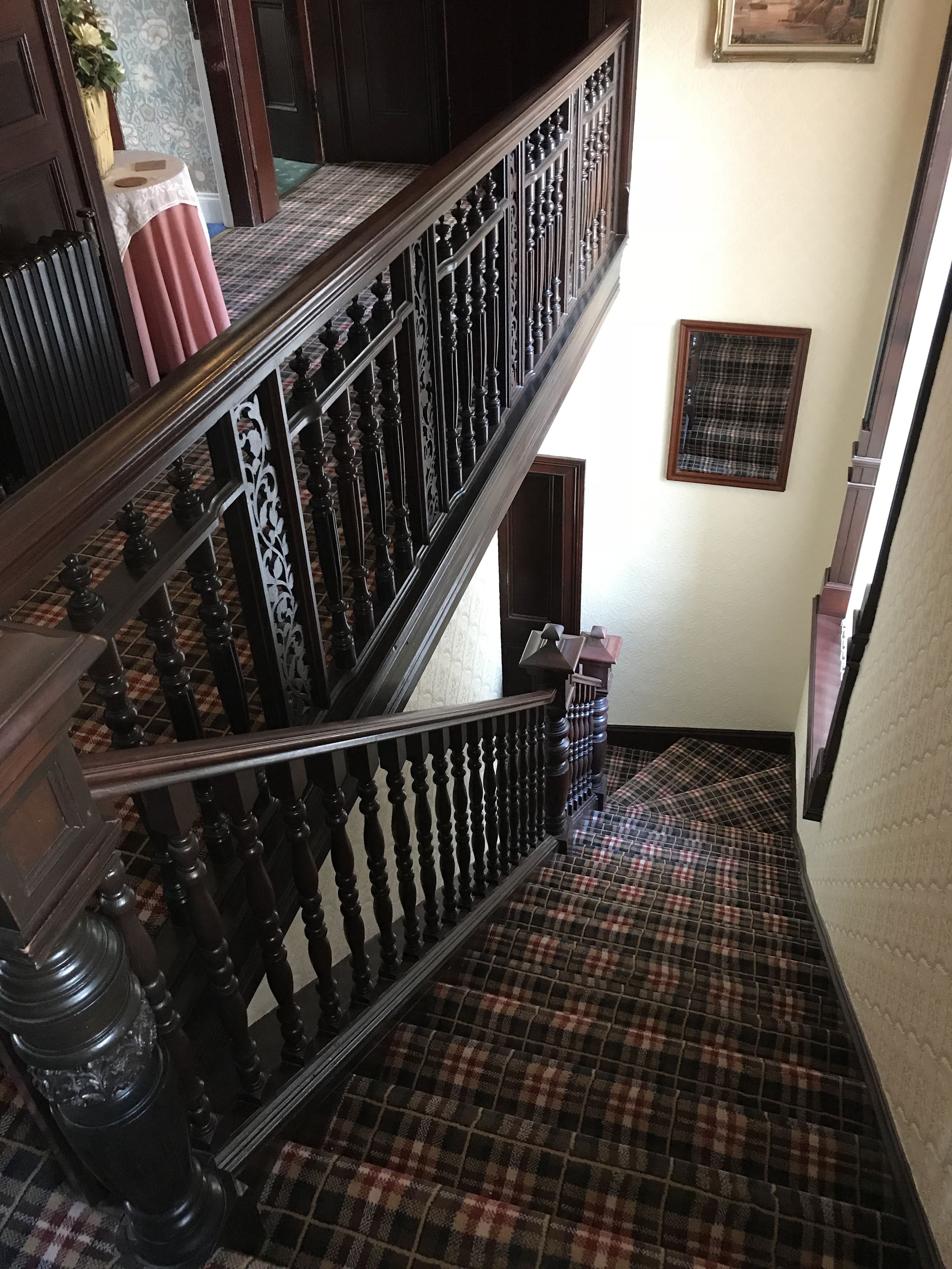 A staircase with a checkered floor and dark wooden balustrades.