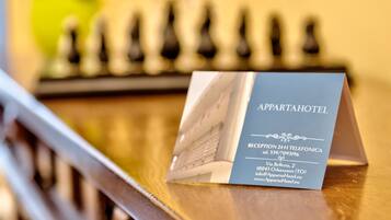 A business card for Apparta Hotel with reception phone number and address.