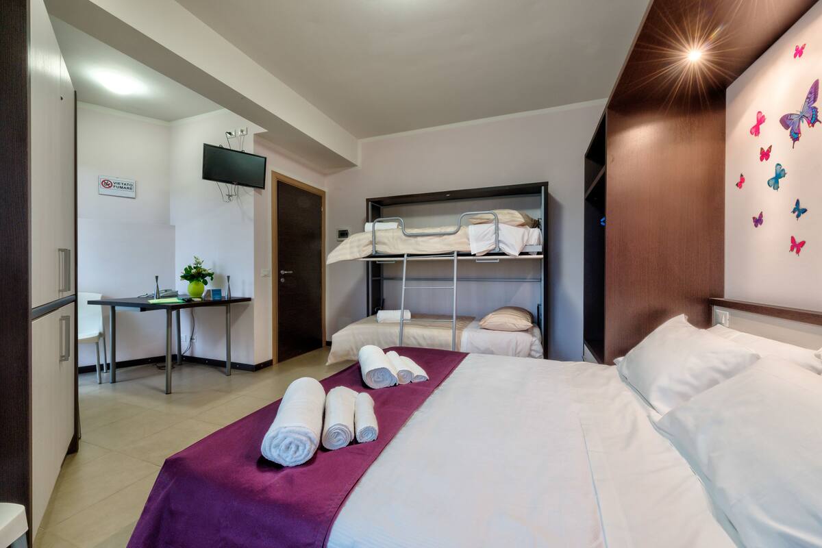 A hotel room with a bed, a desk, and a TV.