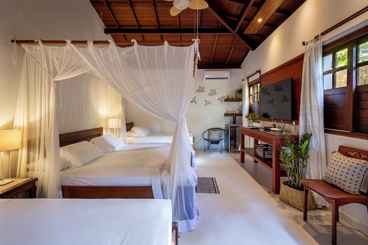 A bedroom with two beds, a wooden ceiling, a TV, and a desk with a chair.