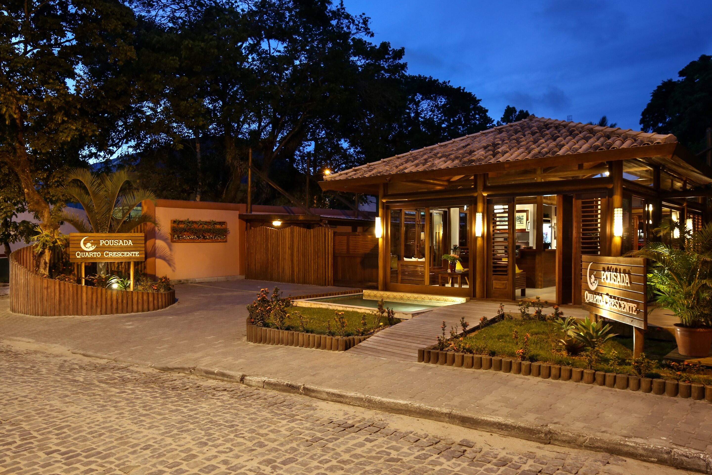 A hotel entrance with a tiled roof, a signboard, and a landscaped garden area.