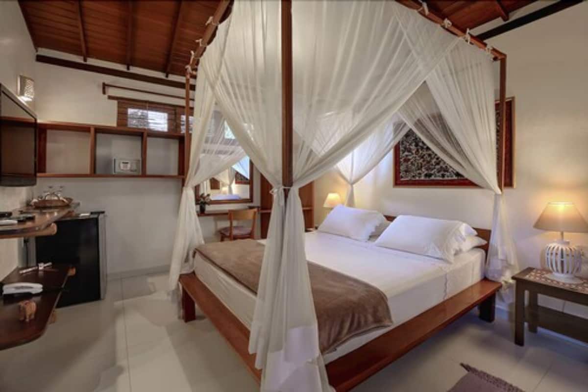 A bedroom with a canopy bed, a desk, and a chair.