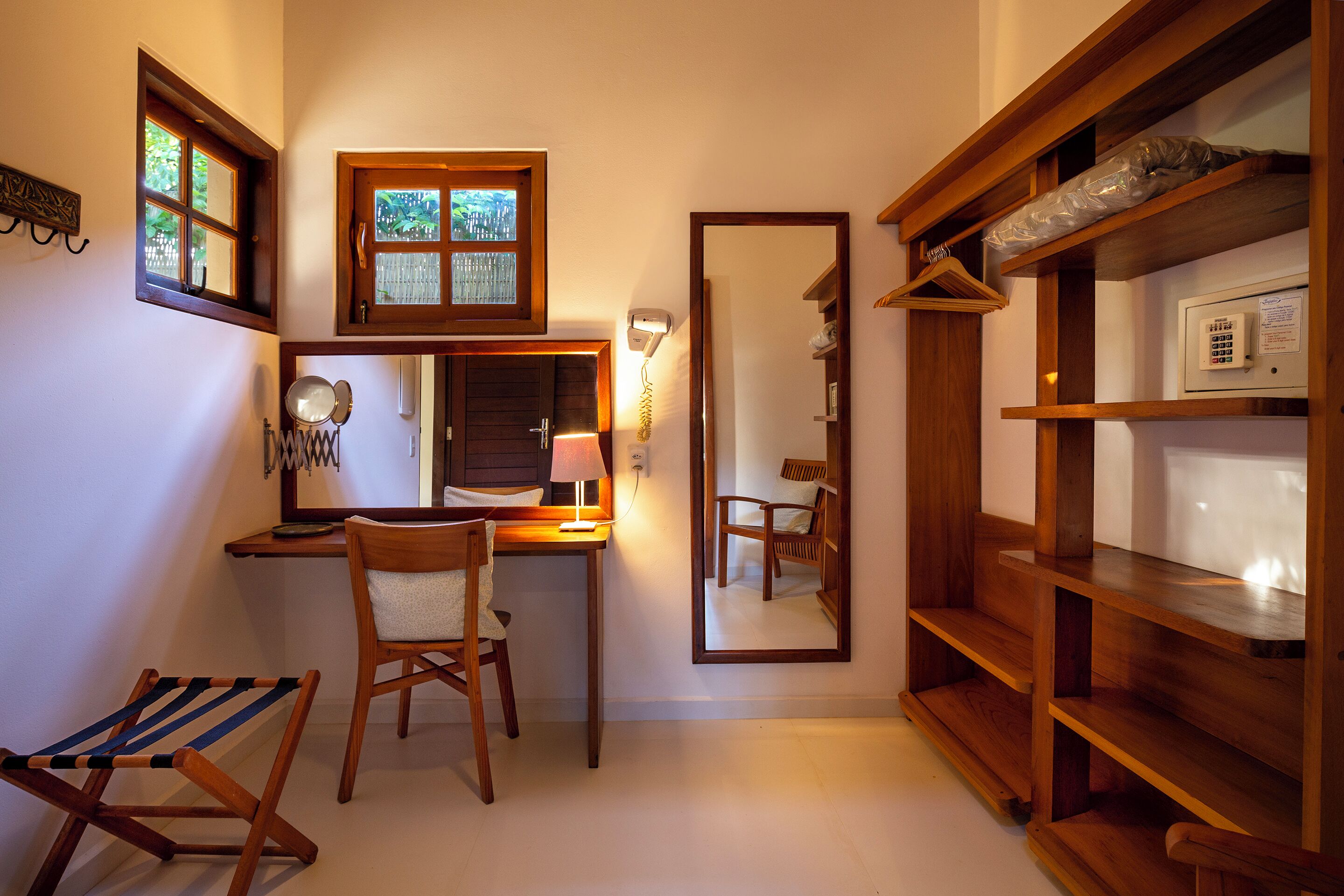 Een kleine kamer met een bureau, stoel en spiegel.
