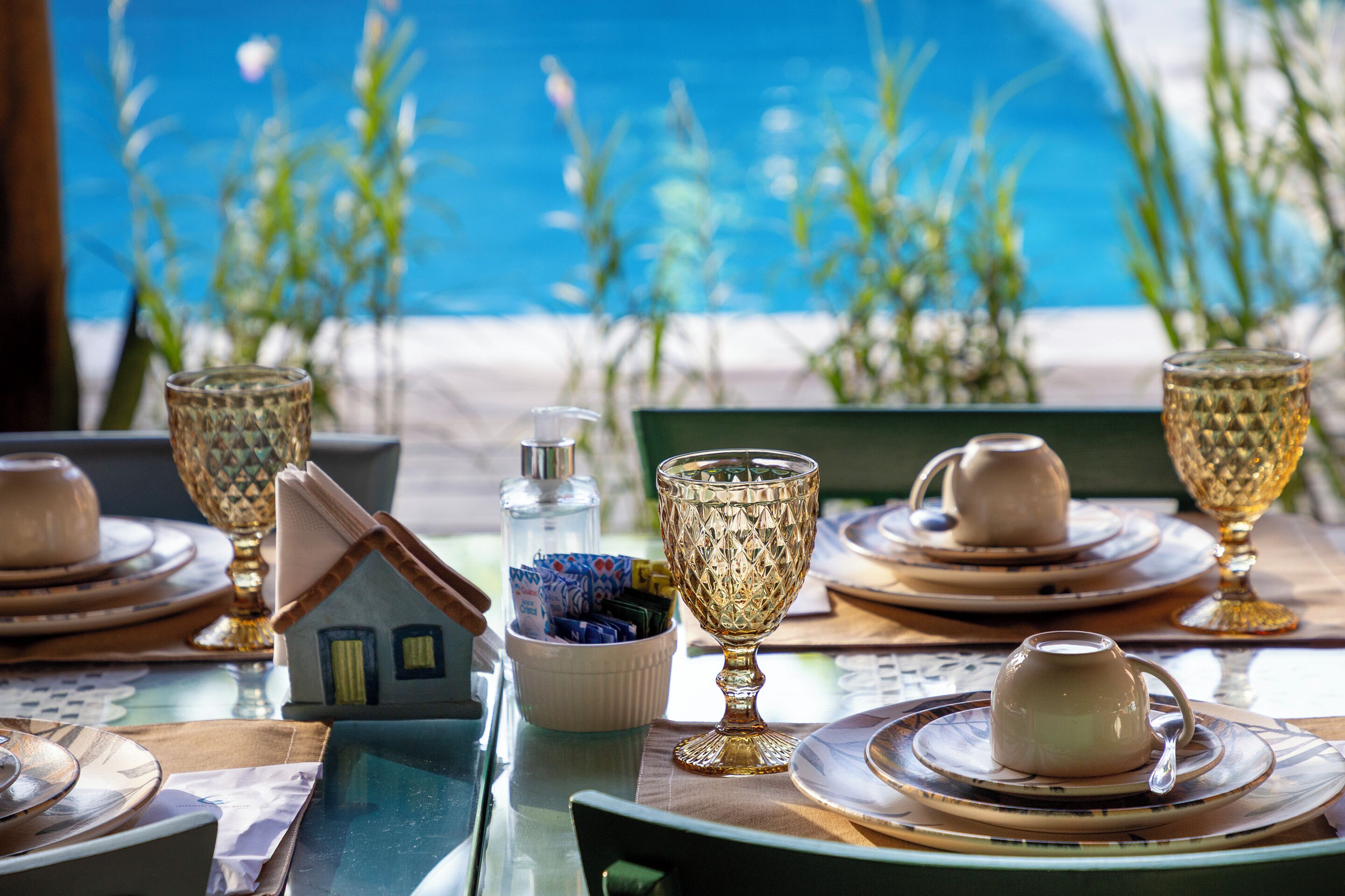 A table set with fine china, crystal glassware, and a small house-shaped salt shaker.
