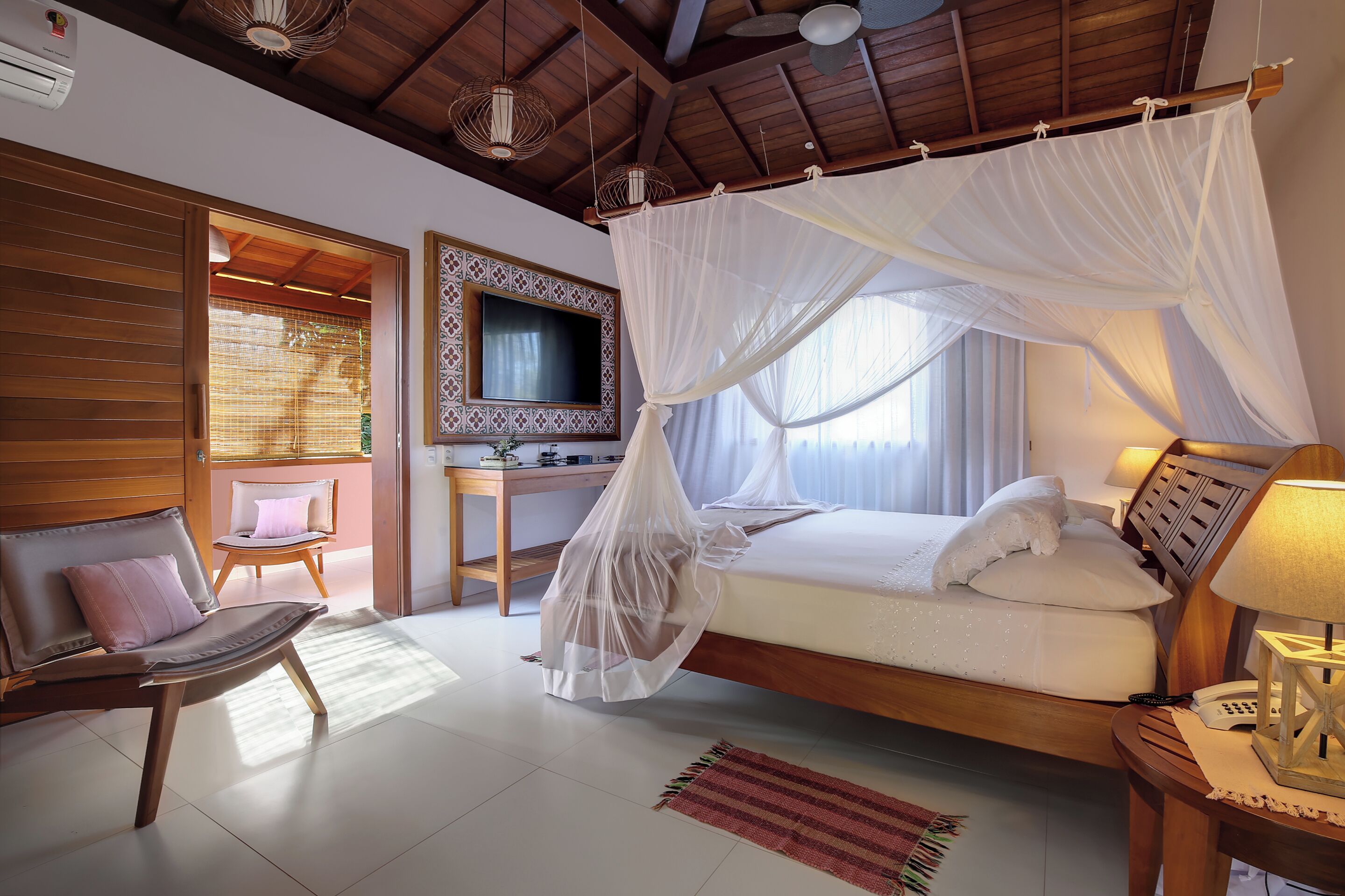 A bedroom with a canopy bed, a desk, a chair, and a television.