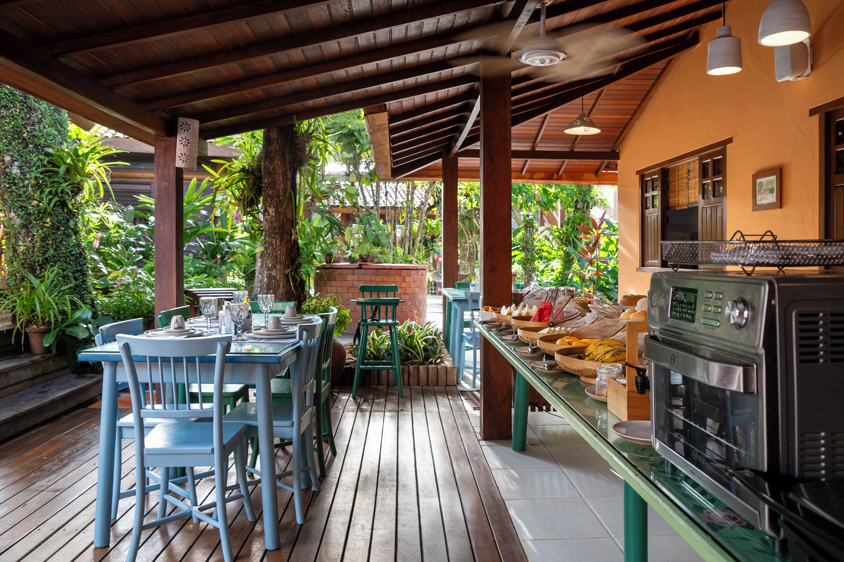An outdoor patio with wooden tables and chairs, a brick planter, and a commercial oven.