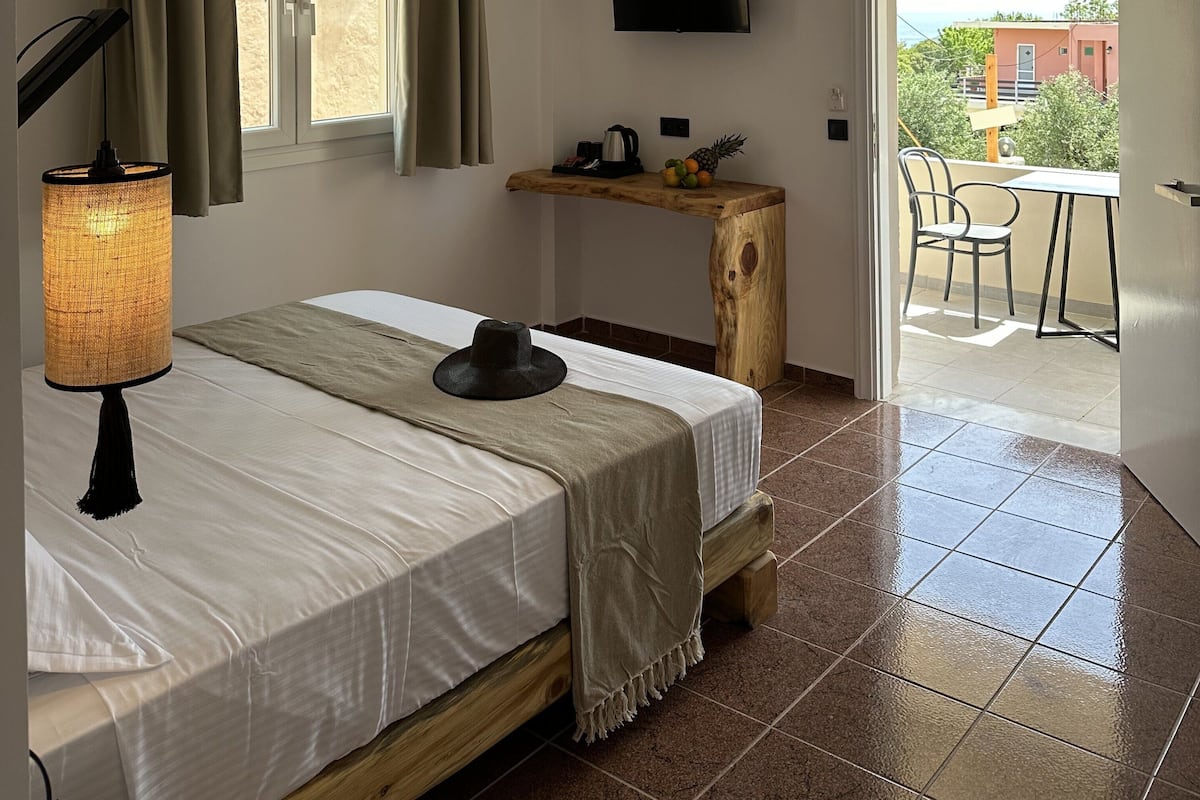A bedroom with a bed, a bedside lamp, a TV, and a small table with a fruit bowl.