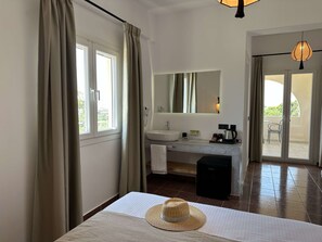Une chambre d’hôtel avec un lit, une salle de bain comprenant un lavabo et un miroir, et une vue sur l’extérieur.