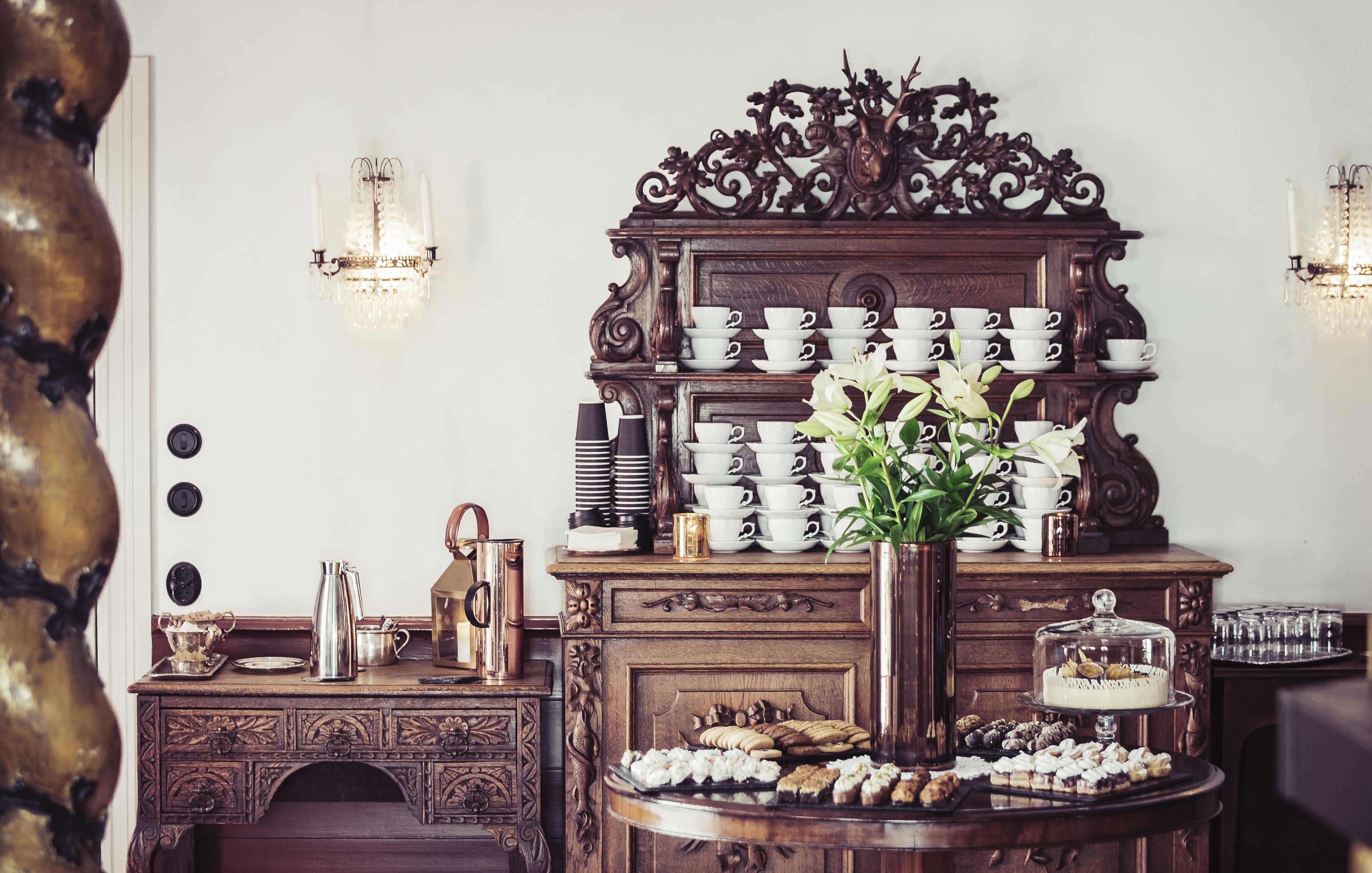 A wooden buffet table with a variety of pastries and a vase of flowers.