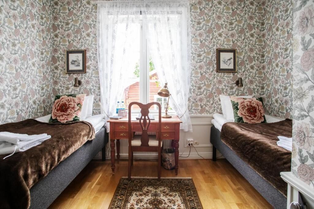 A bedroom with two single beds, a wooden desk, and a chair.