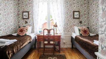 A bedroom with two single beds, a wooden desk, and a chair.