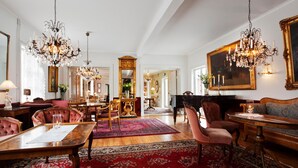 A spacious room with a grand piano, elegant chandeliers, plush seating, and a large mirror. - Grythyttans Gästgivaregård (Grythyttan)