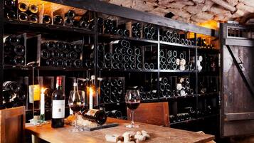 Una cantina vinicola con scaffali di bottiglie di vino e un tavolo con bicchieri da vino e tappi.