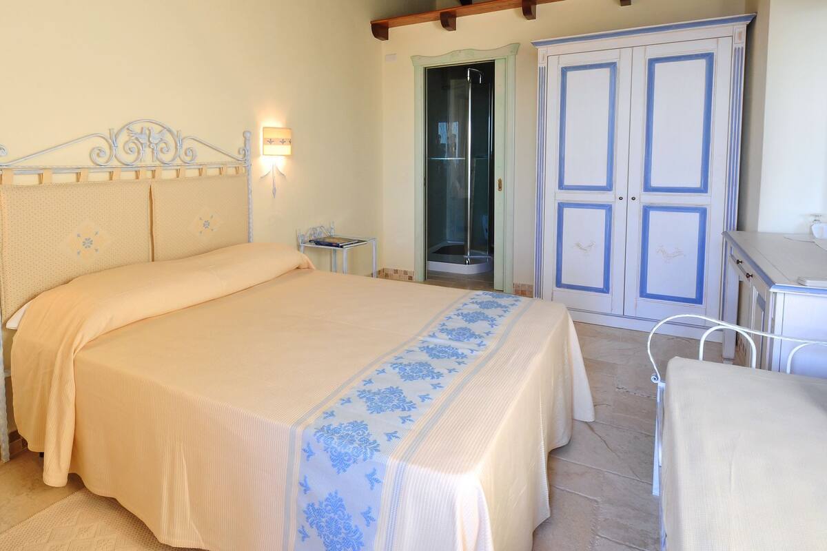 A bedroom with a bed, bedside tables, a wardrobe, and a bathroom with a shower.