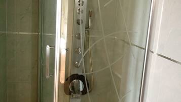 A glass-enclosed shower stall with a handheld showerhead, a handheld shower attachment, and a handheld scrubber.