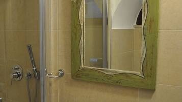 Une salle de bain avec une douche, un lavabo et un miroir doté d’un cadre vert.