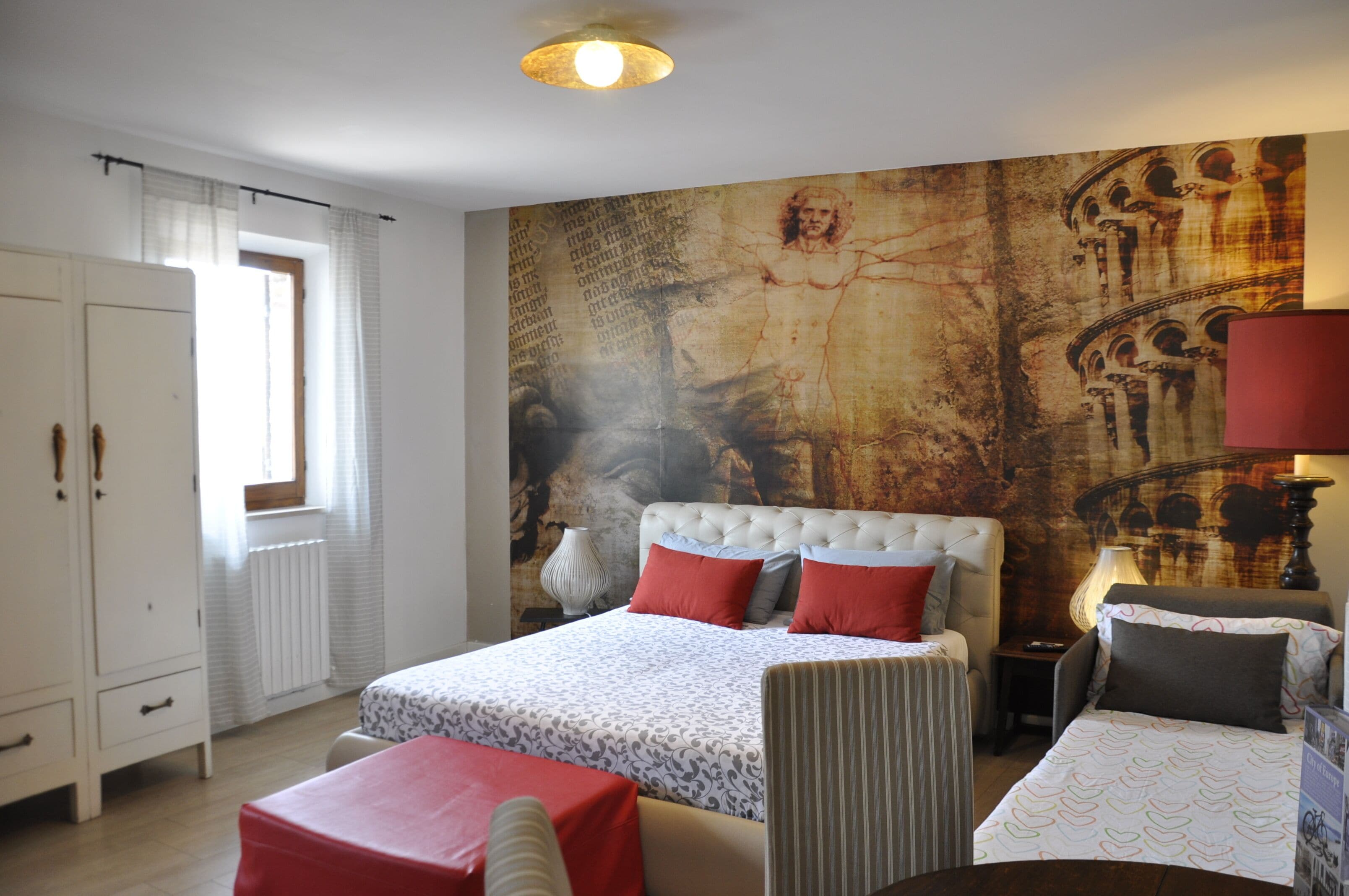 A bedroom with a large bed, a chair, a small table, and a wardrobe.