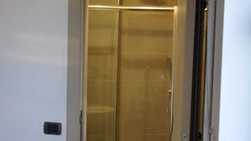 Een moderne badkamer met een douchecabine van glas, een toilet en een ingebouwd wastafelmeubel.