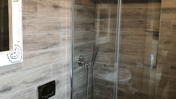 A modern bathroom with a glass-enclosed shower, a white sink, and a mirror with ornate detailing. - B&B Albornoz (Urbino)